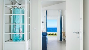 Una stanza con un letto, un armadio e vista sul mare attraverso una porta aperta.