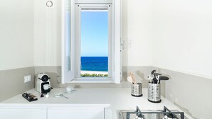 Una cucina moderna con vista sul mare, dotata di macchina del caffè, utensili e piano cottura a gas.