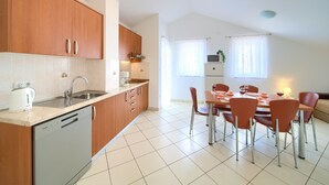Eine moderne Küche mit Holzschränken, einem Geschirrspüler und einem Essbereich mit Tisch und Stühlen.