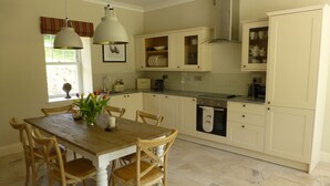 A kitchen with a wooden table and chairs, a window with curtains, and a built-in oven. - Award Winning Ideal Rural Escape in Earn Valley 5 min from Perth (Perth)