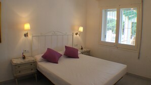 Een slaapkamer met een bed, twee nachtkastjes, twee wandlampen en een raam met uitzicht.