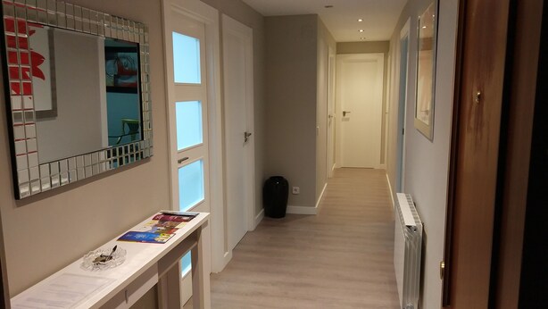 A hallway with a white door, a black trash bin, and a white console table with magazines. - FULL CENTER REFURBISHED 6 SEATS WIFI. 3 MINUTES FROM LAUREL STREET WALKING (Logroño)