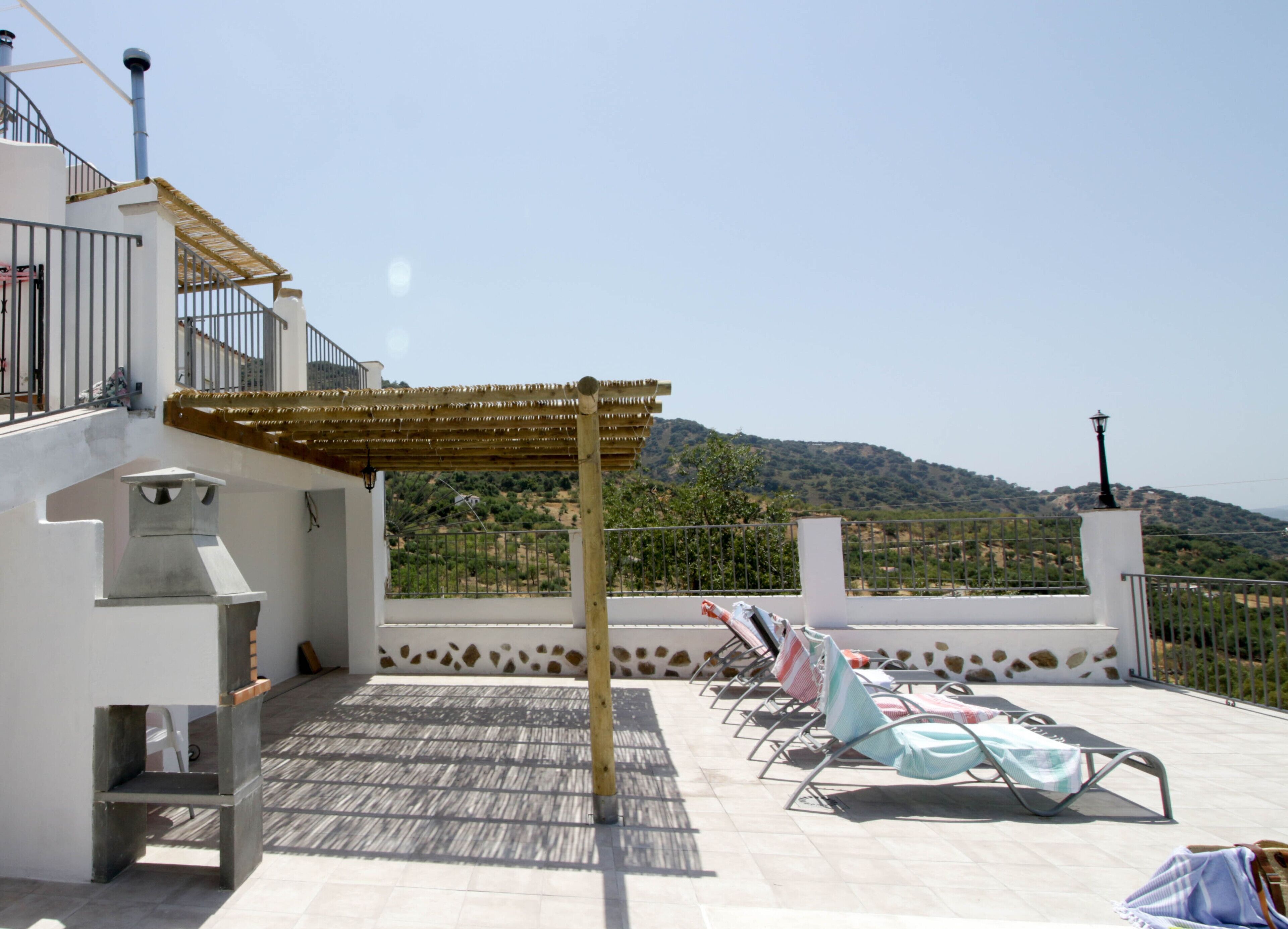 Eine Dachterrasse mit Pergola, Lounge-Stühlen und Blick ins Grüne.