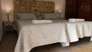 Un letto matrimoniale con una coperta decorata, due comodini con lampade e una testiera in legno.