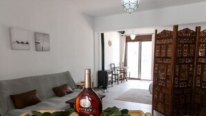 Un soggiorno con un divano, un vassoio di legno con bicchieri da vino e una bottiglia di Mateus.