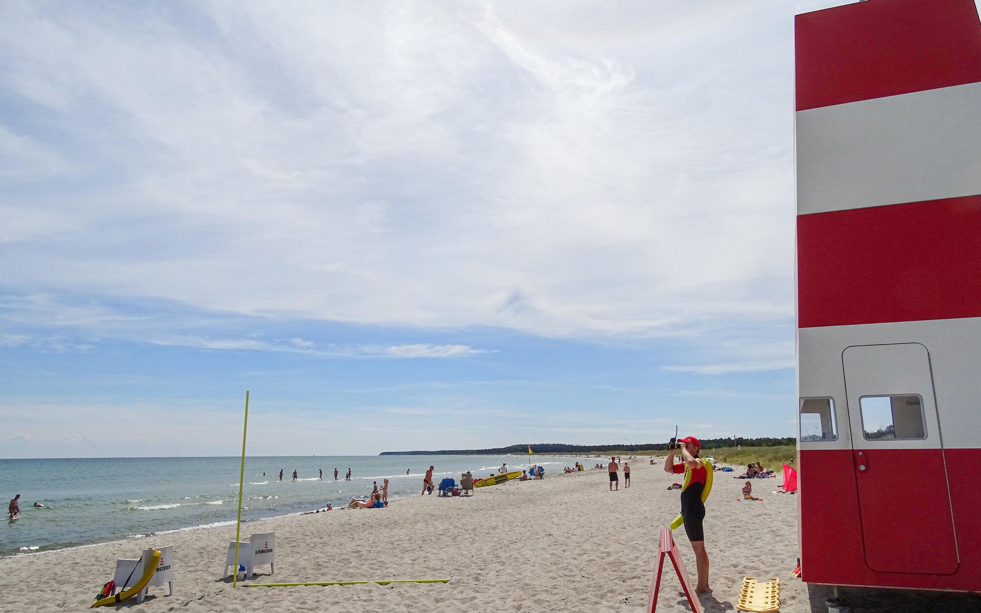 Une plage équipée d’un poste de surveillance pour les sauveteurs, de chaises longues et de parasols.