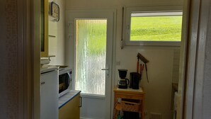 A compact kitchen with a microwave, a coffee maker, and a window with a view of a green field.