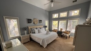 A bedroom with a bed, nightstands, a desk, a chair, and a ceiling fan. - Spacious Sea Pines home - professionally decorated - Private Pool/Hot Tub (Hilton Head Island)
