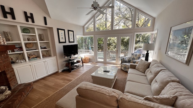 A spacious living room with a high ceiling, large windows, a fireplace, and a cozy seating area. - Spacious Sea Pines home - professionally decorated - Private Pool/Hot Tub (Hilton Head Island)