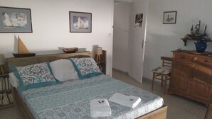 A bedroom with a bed, a wooden dresser, a chair, and a desk. - Downtown apartment (Hyères)