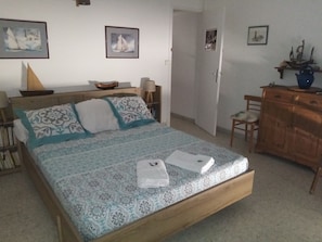 A bedroom with a bed, a wooden dresser, a chair, and a desk.
