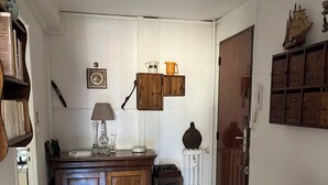 A narrow hallway with a wooden cabinet, a small table, and a wall-mounted shelf. - Downtown apartment (Hyères)