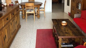 A living room with a wooden dining table, chairs, a sofa, a coffee table, and a cabinet. - Downtown apartment (Hyères)