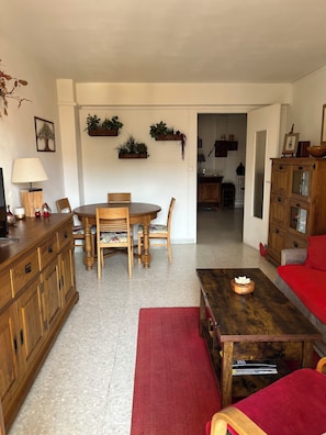 A living room with a wooden dining table, chairs, a sofa, a coffee table, and a cabinet.