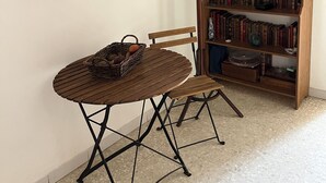 A room with a wooden table, chairs, a bookshelf, and a wall-mounted wooden cabinet with drawers. - Downtown apartment (Hyères)