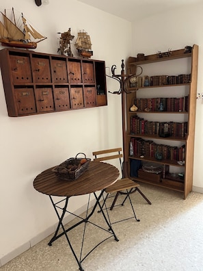 A room with a wooden table, chairs, a bookshelf, and a wall-mounted wooden cabinet with drawers.