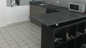 Une cuisine moderne avec des meubles gris, un plan de travail noir, un four à micro-ondes et un évier.