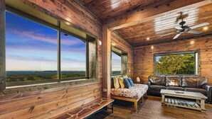 Une cabine spacieuse aux murs en bois, une grande fenêtre offrant une vue panoramique, un canapé en cuir et un banc en bois.