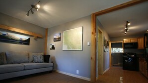 A modern living room with a grey sofa, wooden beams, and a large map on the wall.