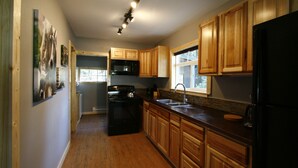 A kitchen with wooden cabinets, a black refrigerator, a microwave, and a stove.