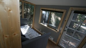 A compact bedroom with a bed, a window, and a door.