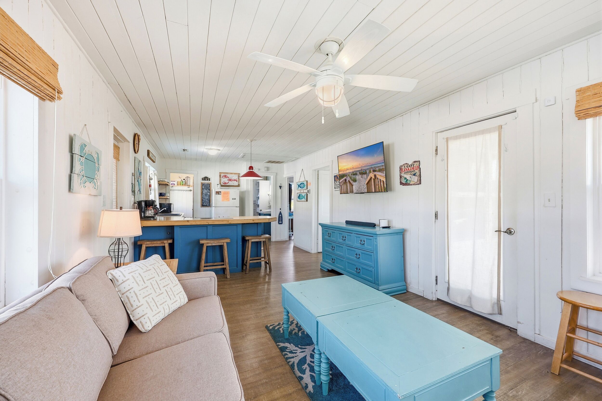 A spacious living room with a sofa, a coffee table, and a kitchen area in the background.