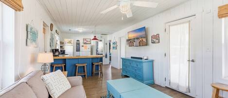 A spacious living room with a sofa, a coffee table, and a kitchen area in the background.