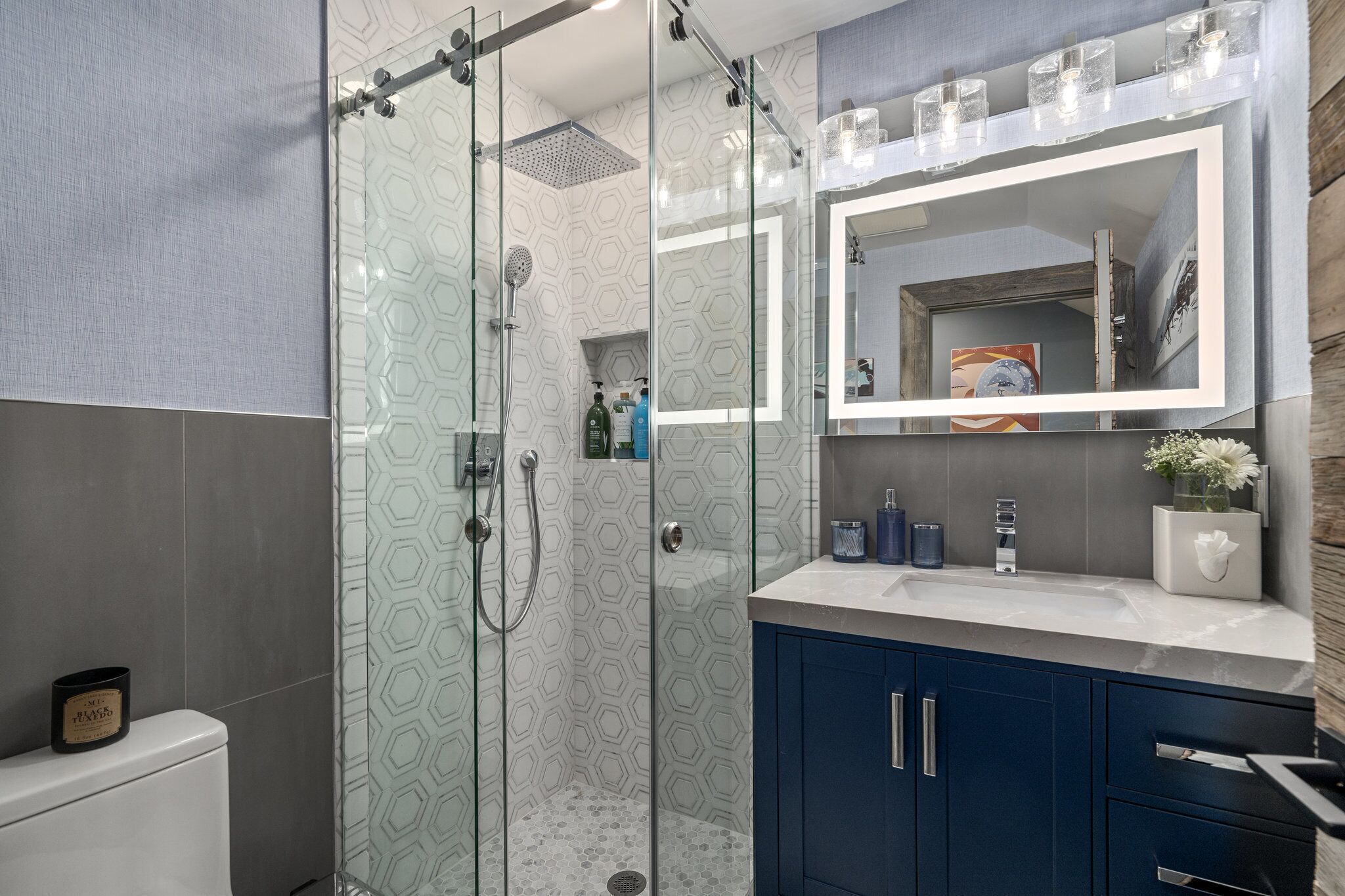 Une salle de bain moderne avec une douche à parois de verre, un meuble-lavabo avec un miroir et des toilettes.