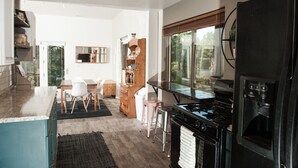A modern kitchen with a central island, a stove, and a refrigerator. There is a dining area with a table and chairs. - The Bright Boho-Tel  (Flagstaff)