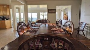 A dining room with a long wooden table, plaid placemats, and matching chairs. There are windows providing natural light and a view of the outdoors. - Kirkwood Ski, Wineries, Caves, Family friendly, near Gold Country (Volcano)