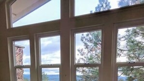 A bedroom with a bed, a window with a view of trees and mountains, and a towel on the floor. - Kirkwood Ski, Wineries, Caves, Family friendly, near Gold Country (Volcano)