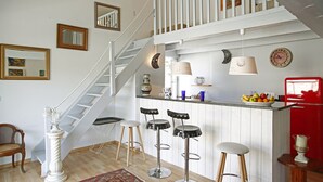 A kitchen with a white staircase, a fruit bowl, and three bar stools. - Charming house - Capo di Vetta (Calvi)
