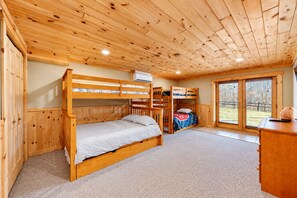 Una camera con un letto a castello, soffitto in legno, una finestra e un termosifone.