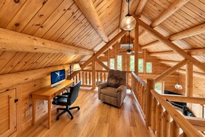Un interior de madera con un escritorio, una silla y una zona de estar acogedora.