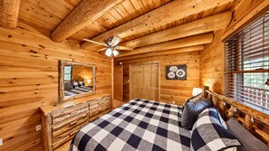 A log cabin bedroom with a bed, dresser, mirror, and a ceiling fan. - Grand Pines Lodge, Luxury Log Home, Views, Hot Tub, Sauna, EV Charger, 3D Tour (Jay)
