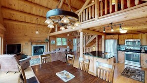 A spacious log cabin interior with a dining area, kitchen, living room, and fireplace. - Grand Pines Lodge, Ultimate Log Luxury, Stunning Views, Hot Tub & Sauna, EV Charger, 3D Tour (Jay)