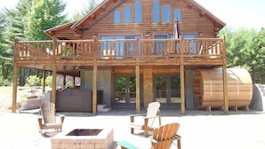 A wooden cabin with a balcony, outdoor seating, and a barrel. - Grand Pines Lodge, Ultimate Log Luxury, Stunning Views, Hot Tub & Sauna, EV Charger, 3D Tour (Jay)