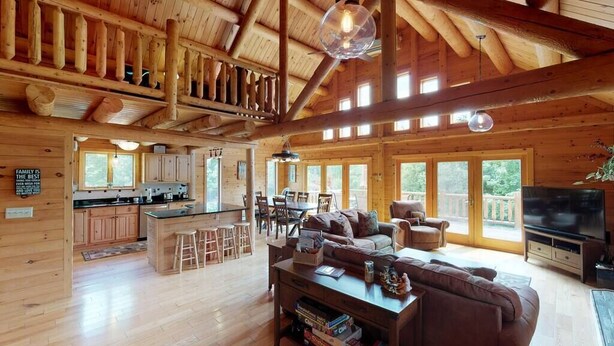 A spacious wooden cabin with a kitchen, dining area, and living room. - Grand Pines Lodge, Ultimate Log Luxury, Stunning Views, Hot Tub & Sauna, EV Charger, 3D Tour (Jay)