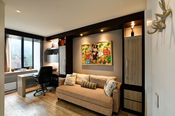 Un salon moderne avec un canapé beige, un fauteuil de bureau noir et un grand tableau abstrait accroché au mur.