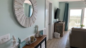 Un salon avec une console en bois, un grand miroir et une vue sur le balcon.