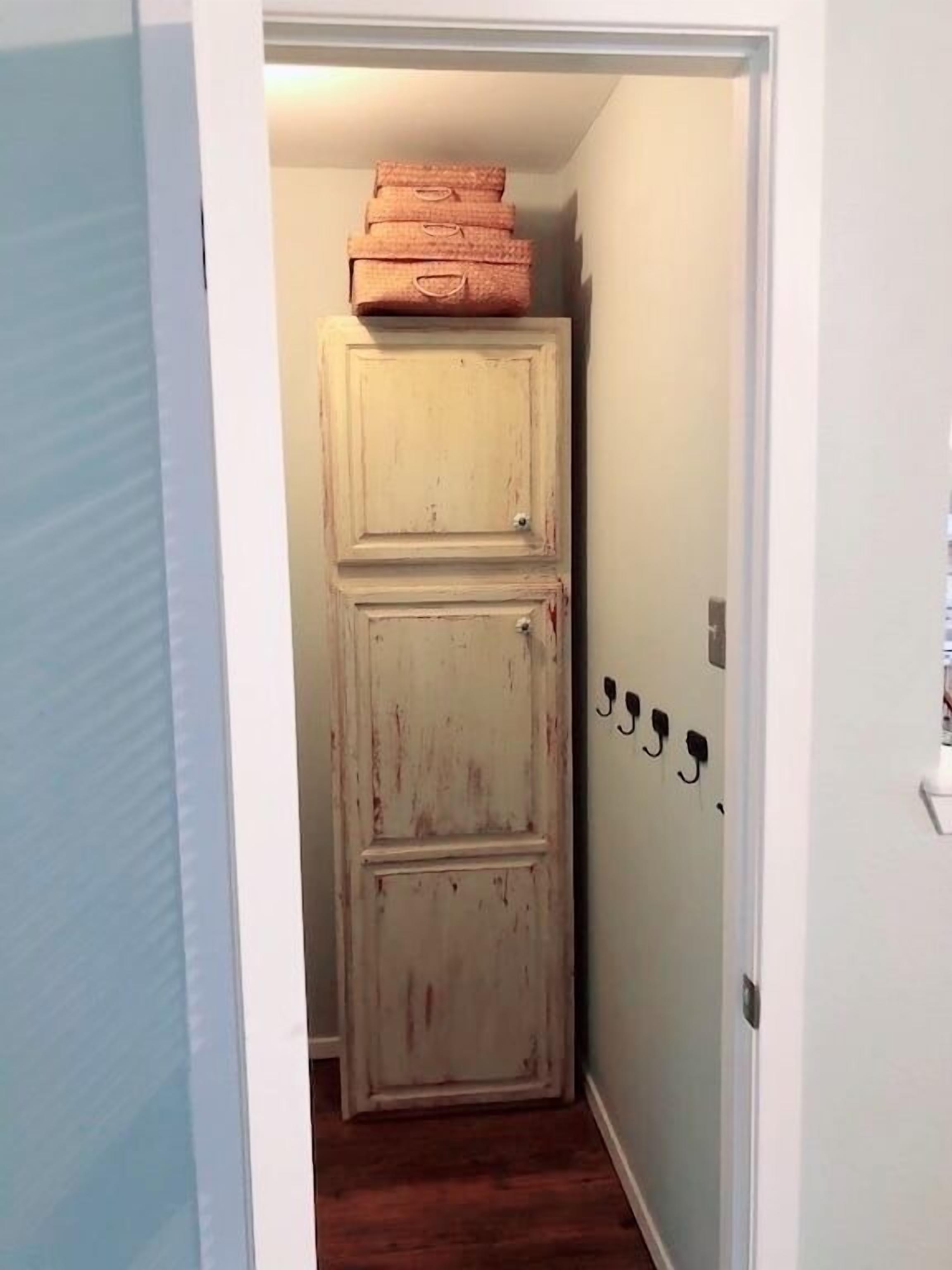 A narrow hallway with a door at the end, a small rug on the floor, and a wall-mounted light fixture.
