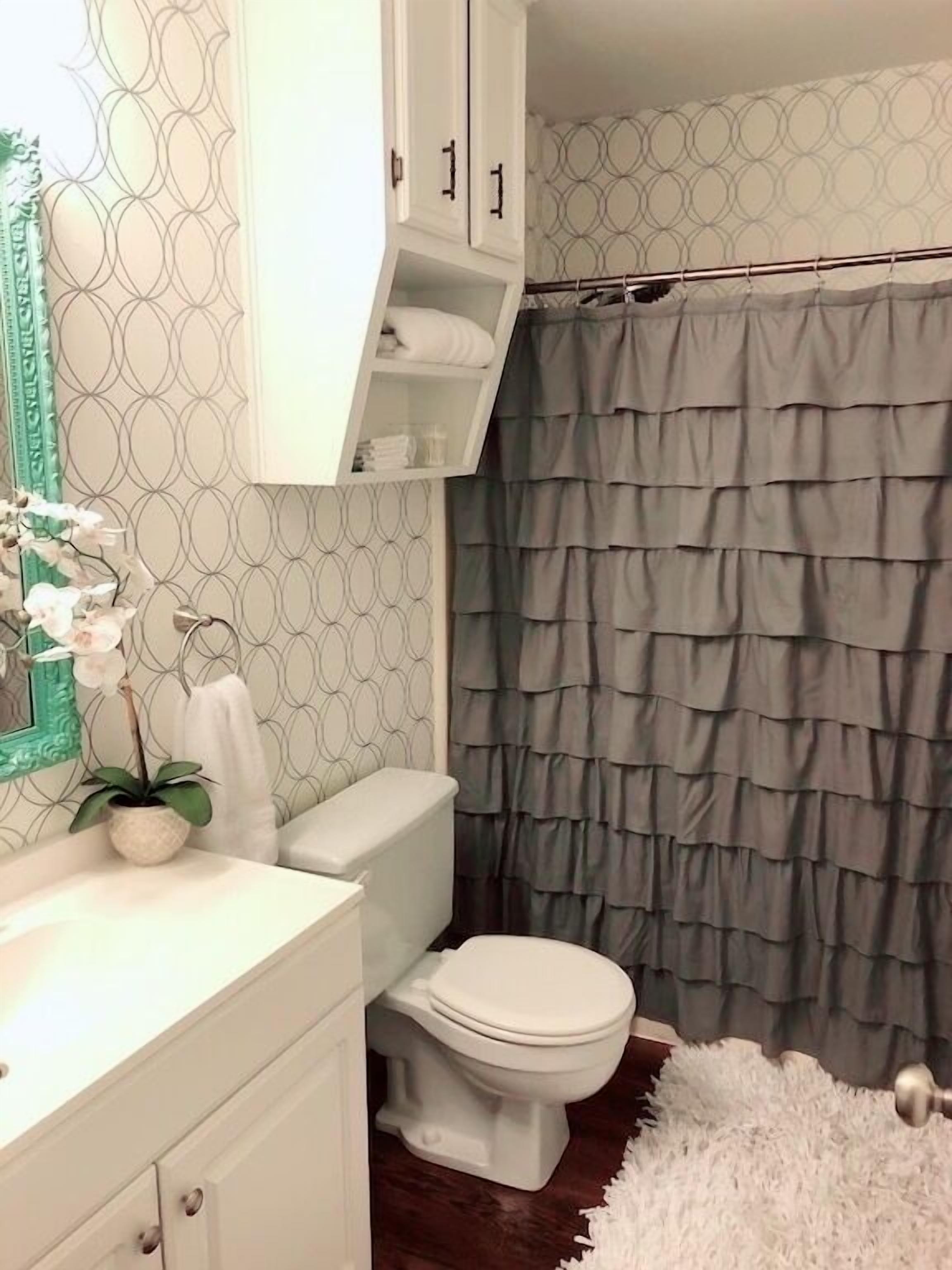 Ein Badezimmer mit Toilette, Waschbecken mit Spiegel und Duschvorhang.