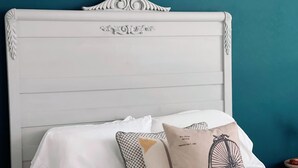 Un lit avec une literie blanche et des coussins décoratifs, dont un avec un motif représentant un vélo.