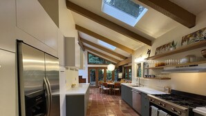 A modern kitchen with a stainless steel refrigerator, a gas stove, and a skylight above the dining area. - Nestled in the Redwoods, Easy Walk Downtown, Close to SF and Wine Country (Mill Valley)