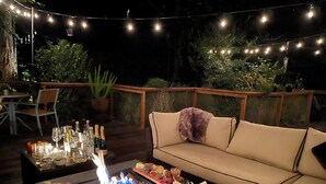 An outdoor dining area with a fire feature, a sofa, and string lights. - Nestled in the Redwoods, Easy Walk Downtown, Close to SF and Wine Country (Mill Valley)