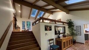 A staircase with wooden railings leading to a landing with a wooden cabinet, a chair, and a potted plant. - Nestled in the Redwoods, Easy Walk Downtown, Close to SF and Wine Country (Mill Valley)