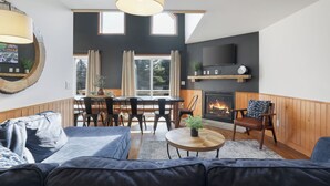 Ein modernes Wohnzimmer mit Kamin, Essbereich und großem Fenster.