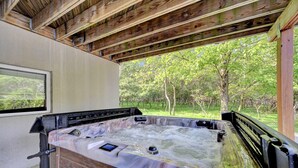 Ein Whirlpool mit Holzverkleidung und Blick auf ein bewaldetes Gebiet durch ein Fenster.
