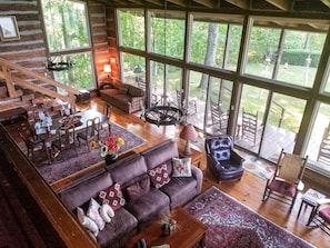 Cozy living area with a large couch, leather armchair, and dining table for four, offering a view of the surrounding landscape.