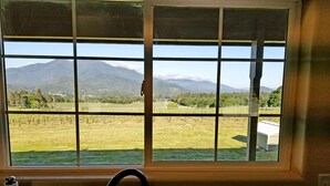 A kitchen with a window overlooking a vineyard and mountains.
